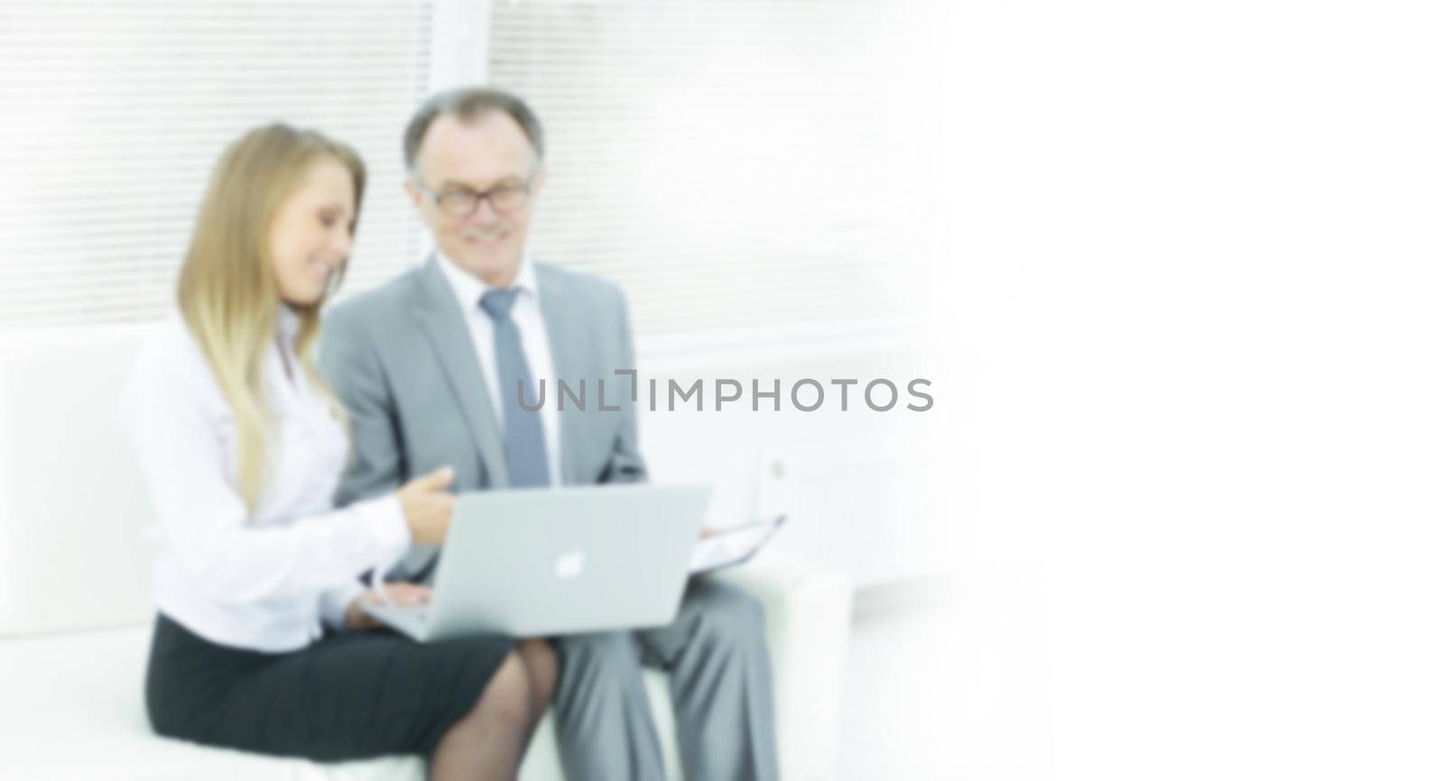 senior businessman and assistant using a laptop sitting in the lobby of the office. by SmartPhotoLab