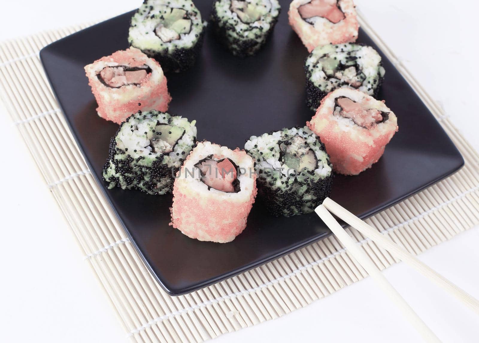 Sushi Set - different types of Maki sushi and chopsticks on a black plate.isolated on white