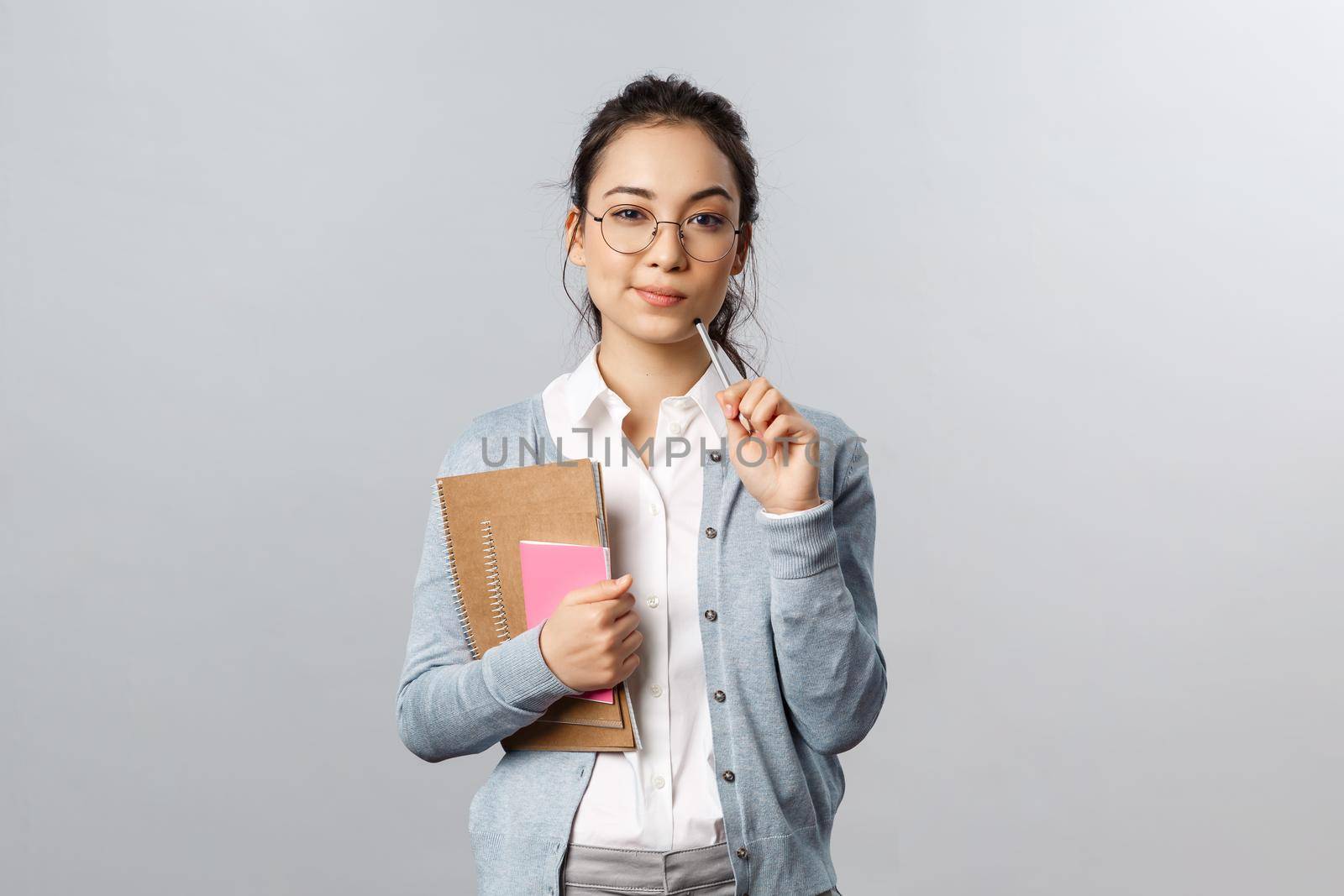 Education, teachers, university and schools concept. Smart and creative young woman, asian tutor preparing new interesting material for class, thinking-up ideas, touch lip with pencil, pondering.
