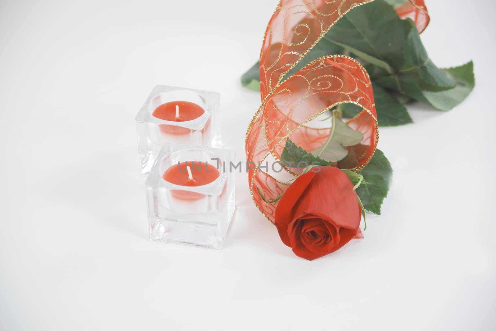 two candles and a red rose on a white background.photo with copy by SmartPhotoLab