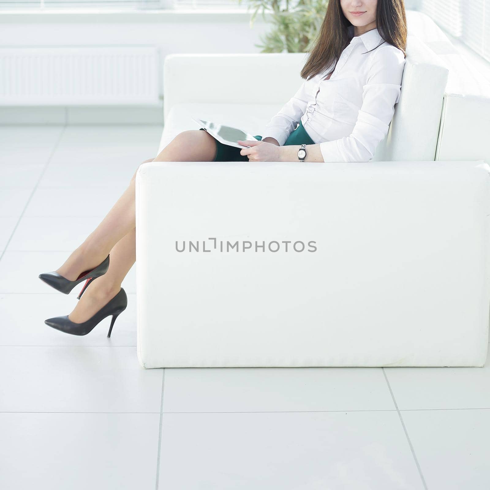 young woman with digital tablet sitting in the lobby of the office.photo with place for text