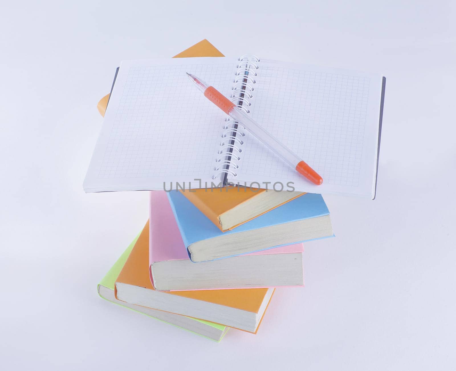 open the notebook, pen and a stack of books on white background.