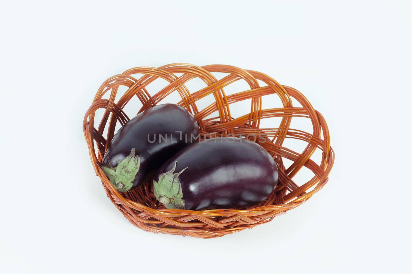 two ripe eggplant in a wicker basket.isolated on white.photo with copy space