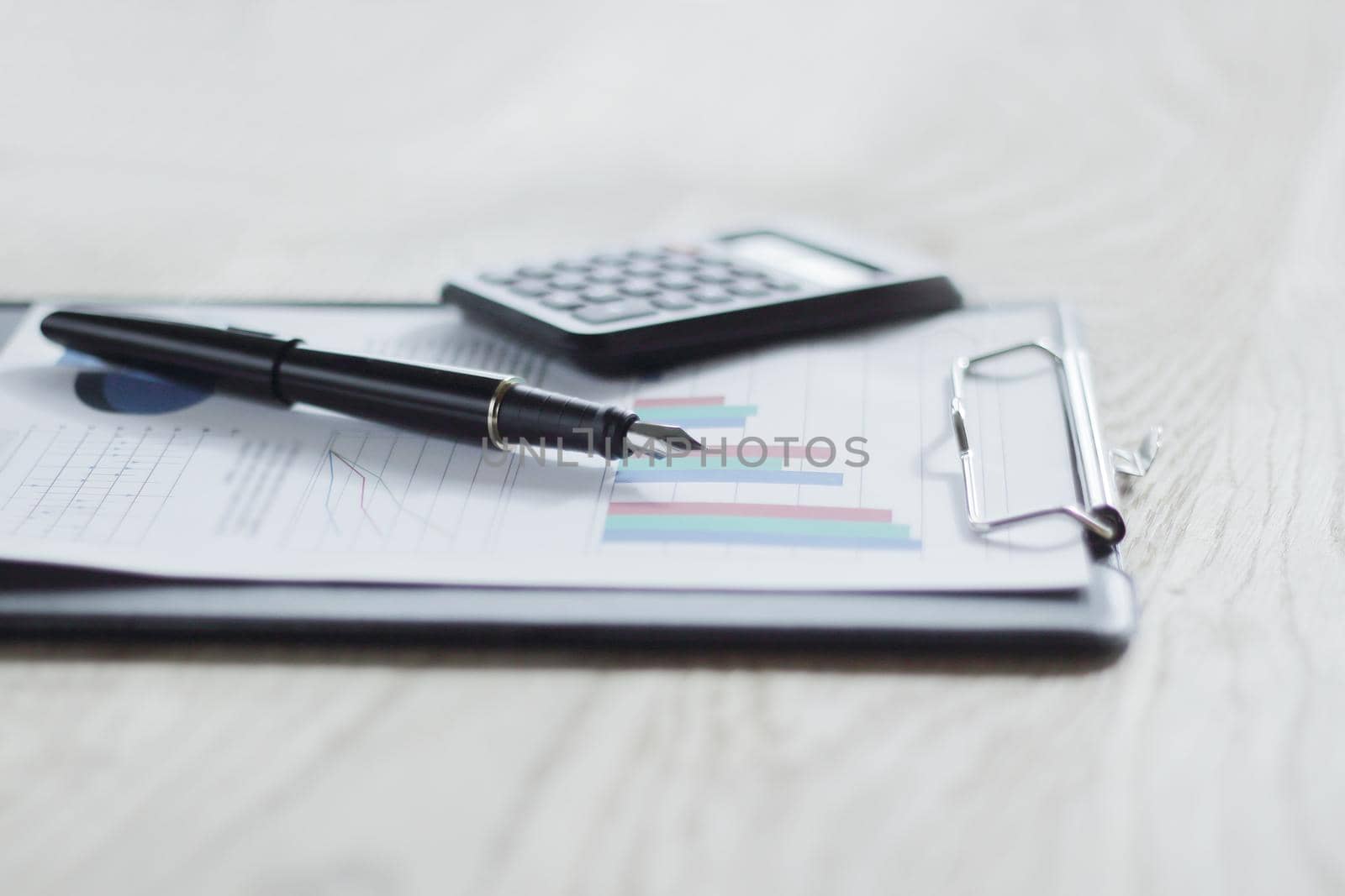 close up. pen, calculator and clipboard on wooden table. busines by SmartPhotoLab