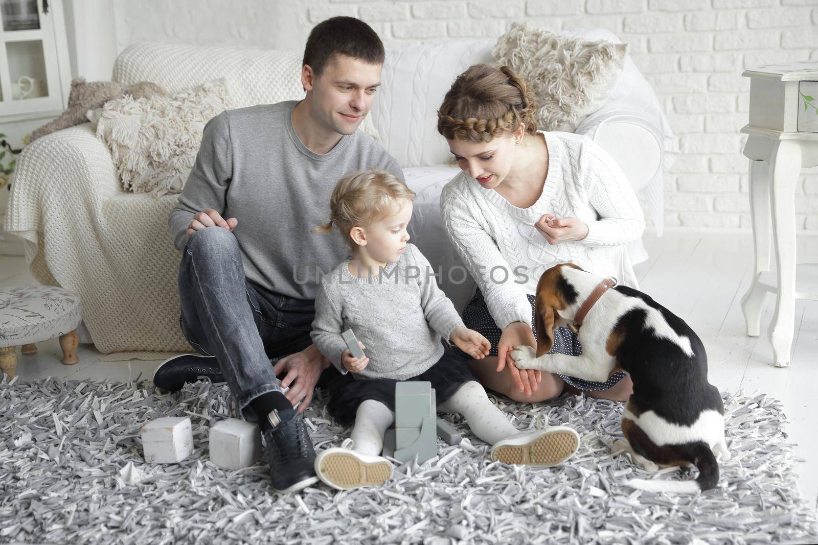 happy parents with a young daughter and pet sitting on the couch.