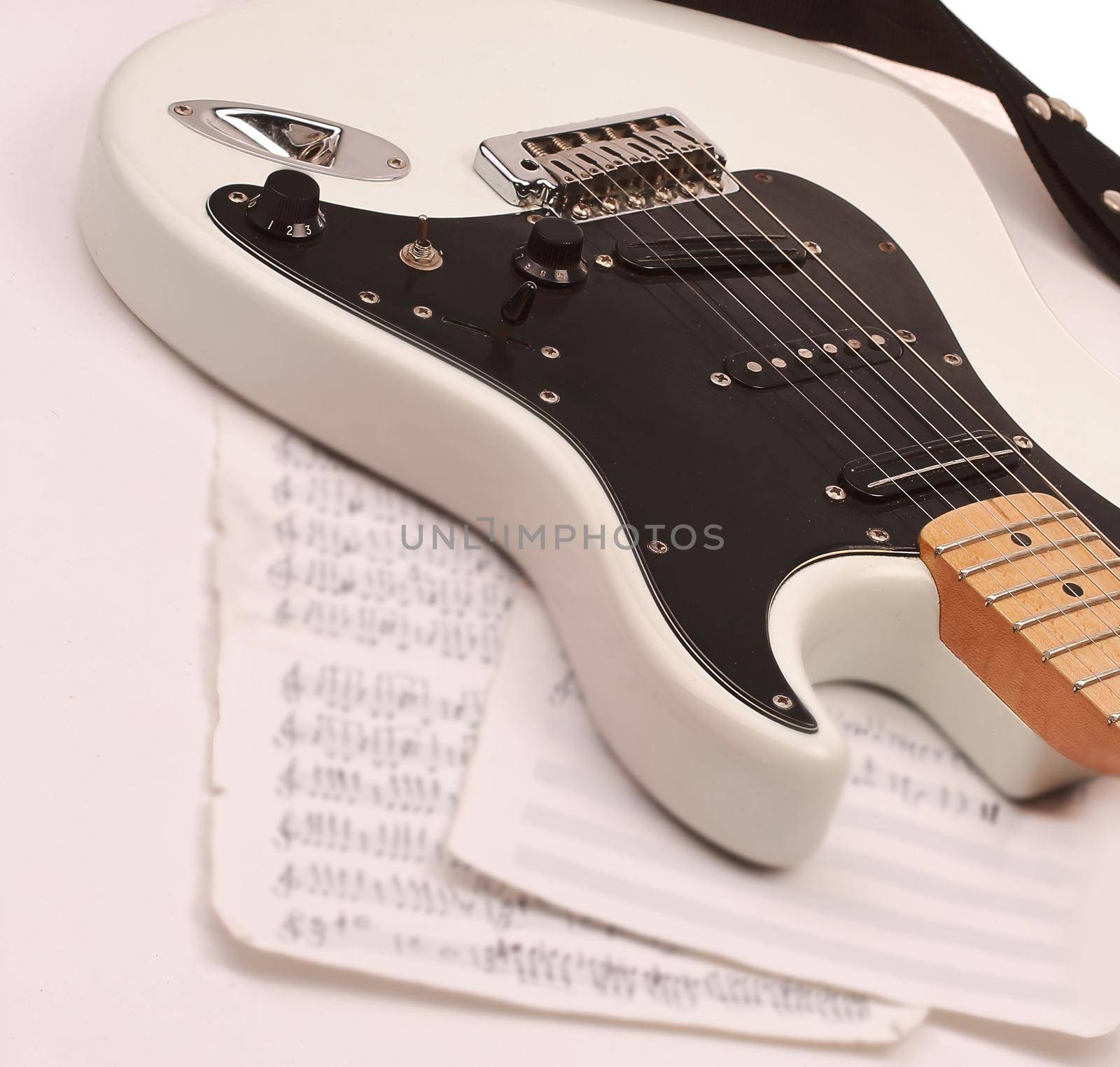 closeup of music sheets and black-and-white electric guitar.iso by SmartPhotoLab
