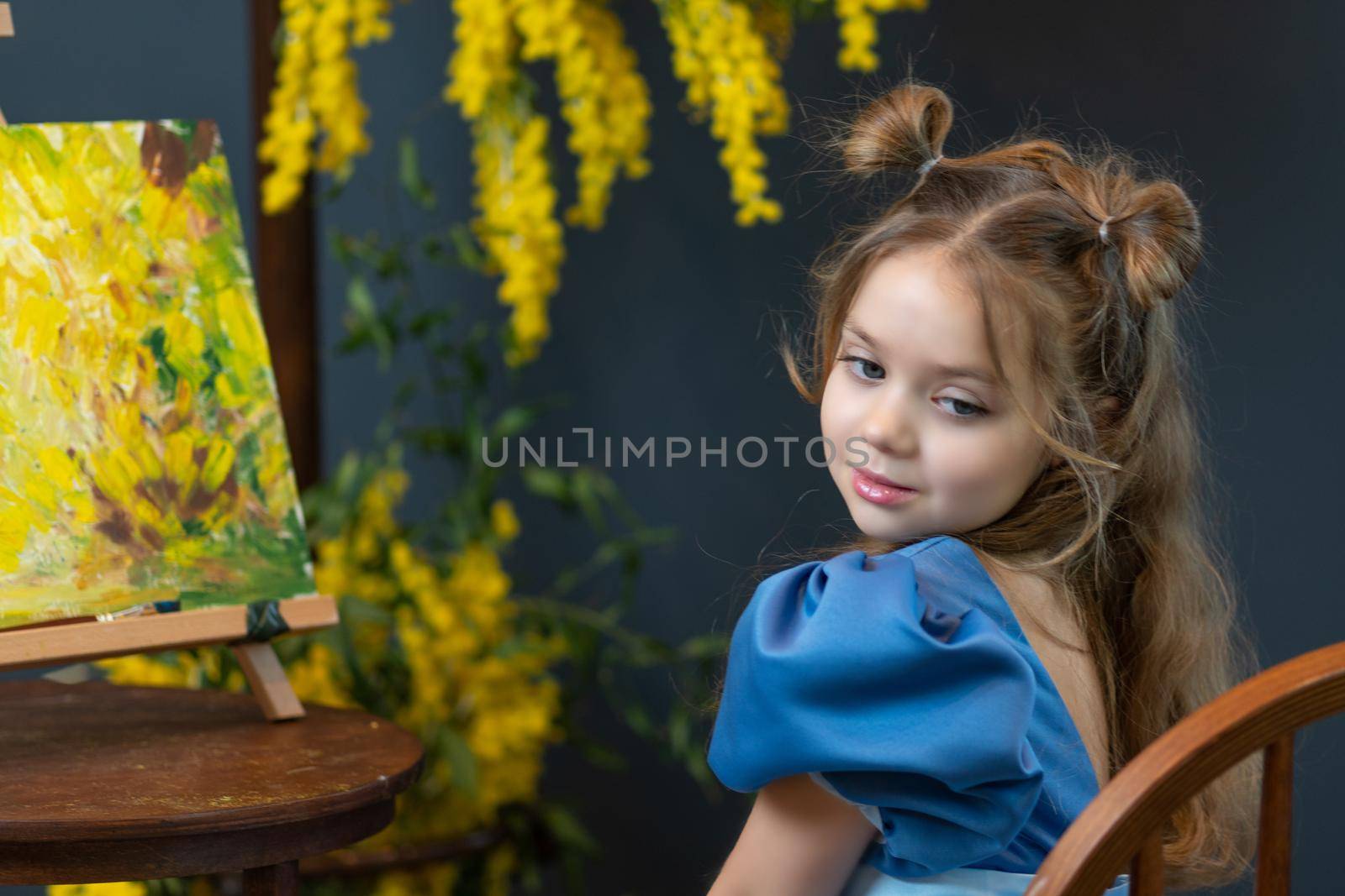 A girl sits near a mimosa and paints a picture in a blue dress mimosa brush little cute, In the afternoon dress holding in white and spring happiness, kid mother. 8 march nature fresh, holiday pretty day picture