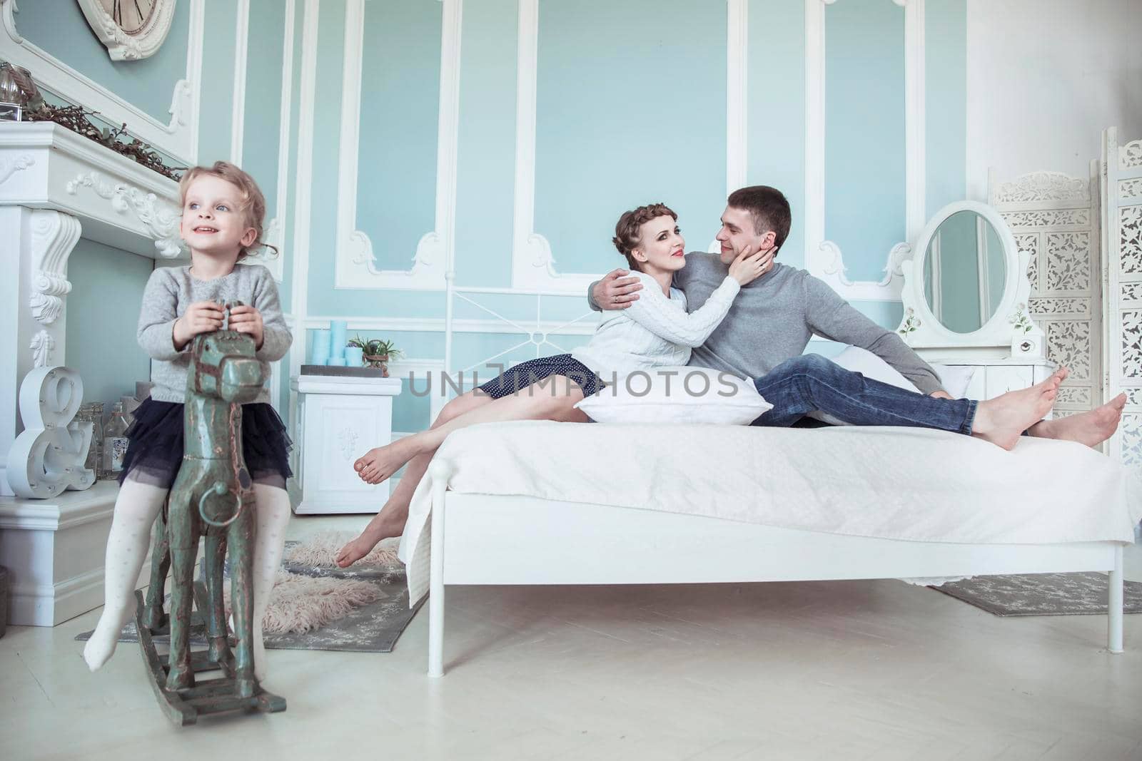 loving parents and their daughter on a wooden horse in the bedroom