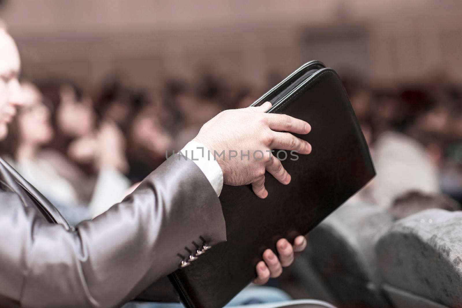 concept of success in business: a successful businessman with a folder for documents sitting in the conference room. by SmartPhotoLab