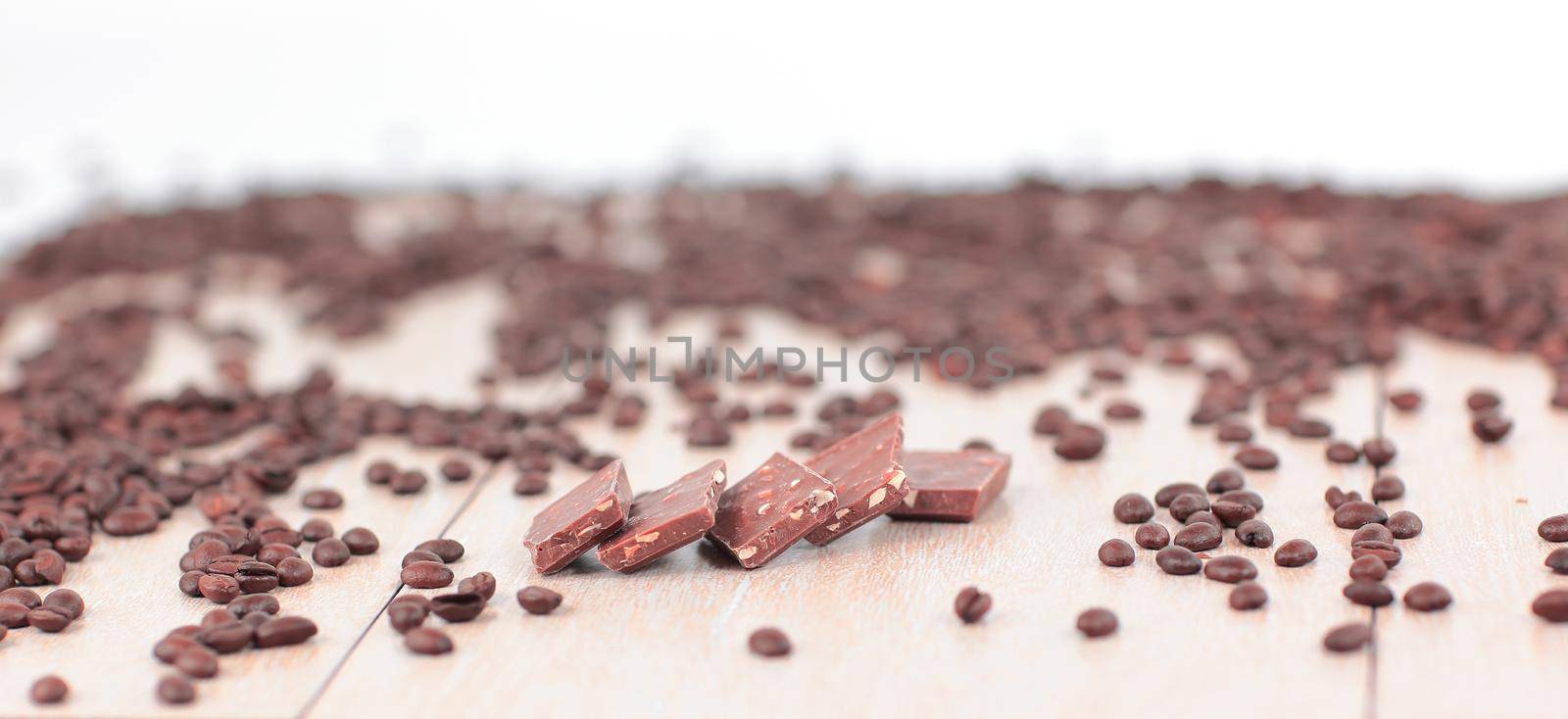 black coffee beans and chocolates on wooden background.