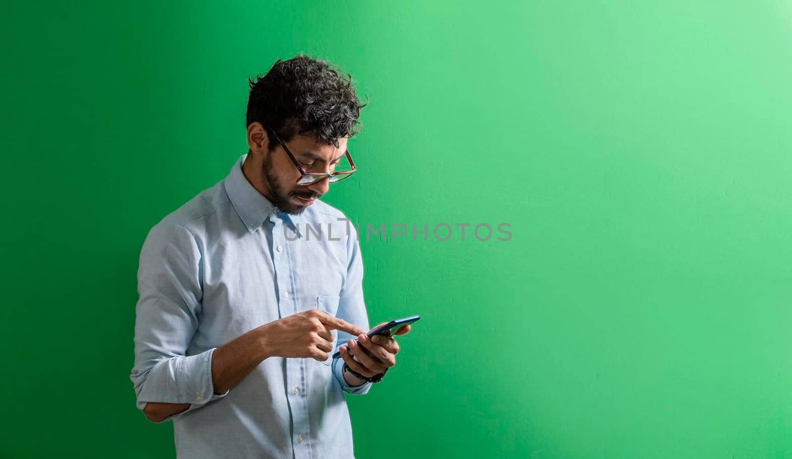 Man checking his cell phone isolated, young man in glasses checking his cell phone isolated by isaiphoto