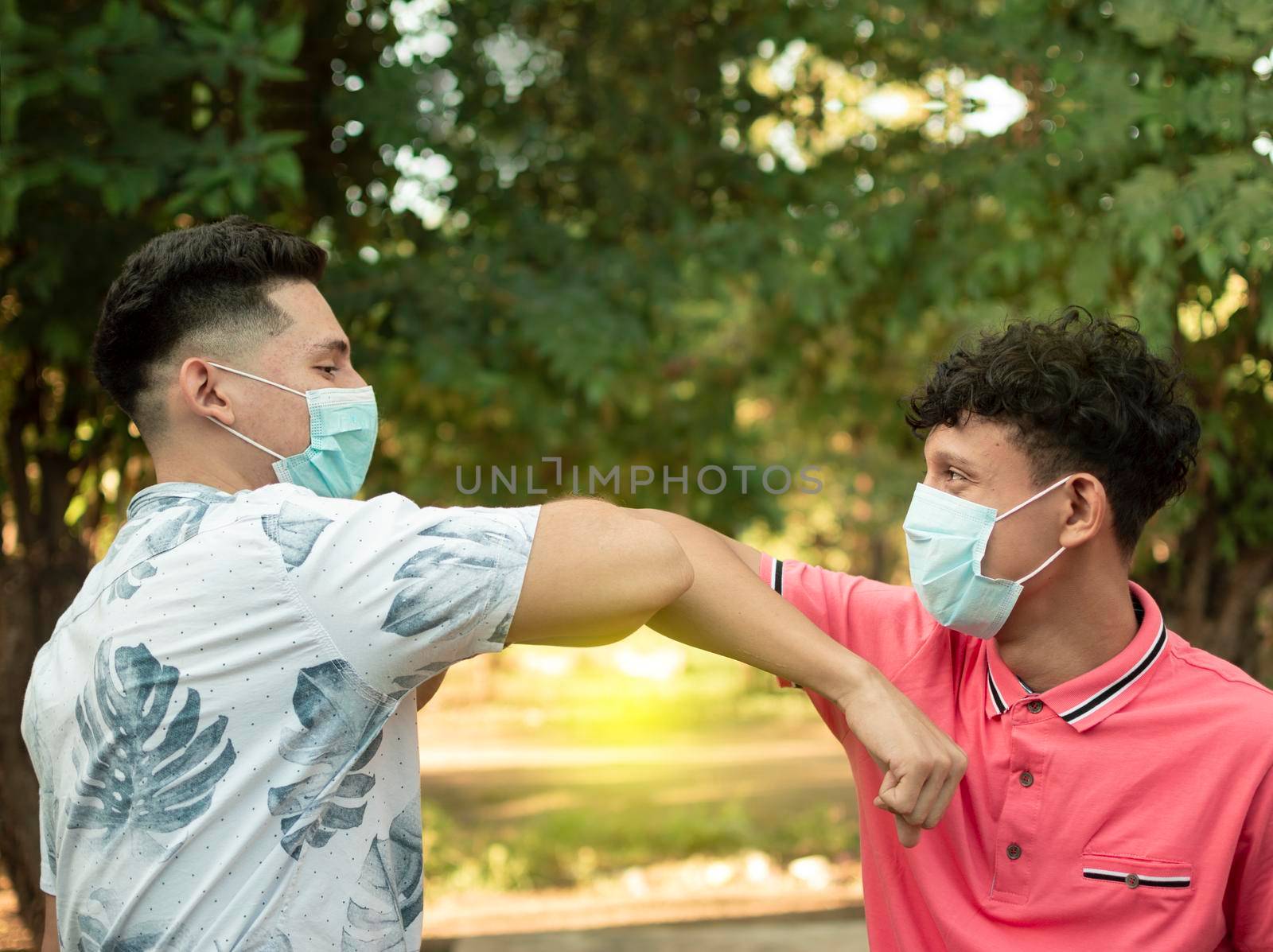 Two young people bumping their elbows, image of two young people bumping their elbows in a friendly way, about two elbows bumping in a friendly way by isaiphoto