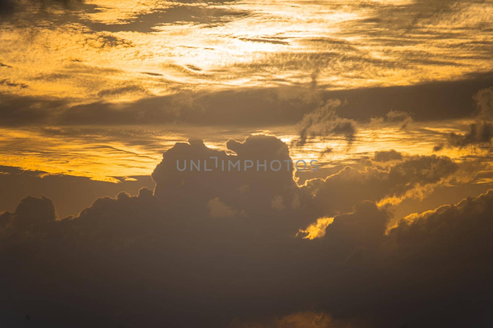 golden coudy sky with towering clouds, sun hidden behind it with the orange glow of sunrise sunset shot in andaman havelock island by Shalinimathur