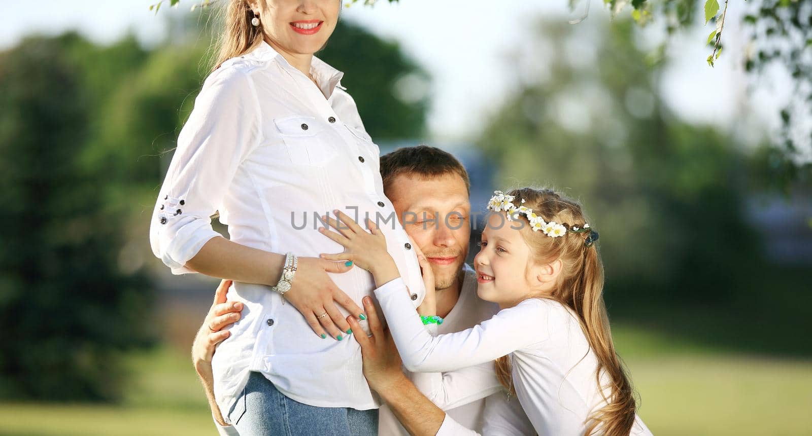 happy father and little girl hugging her pregnant mother on a wa by SmartPhotoLab