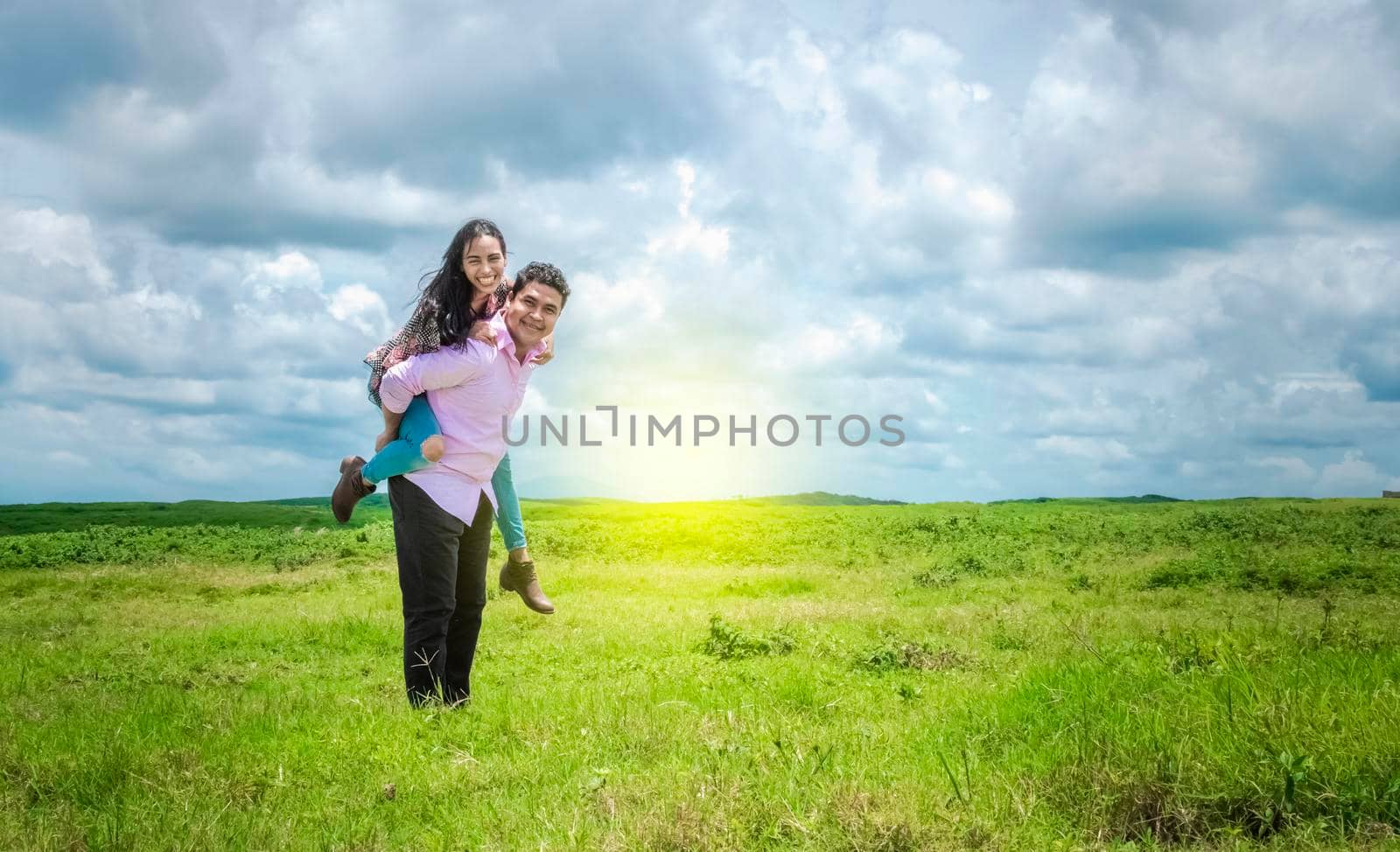 Happy couple in love in the field, happy man carrying his girlfriend in the field