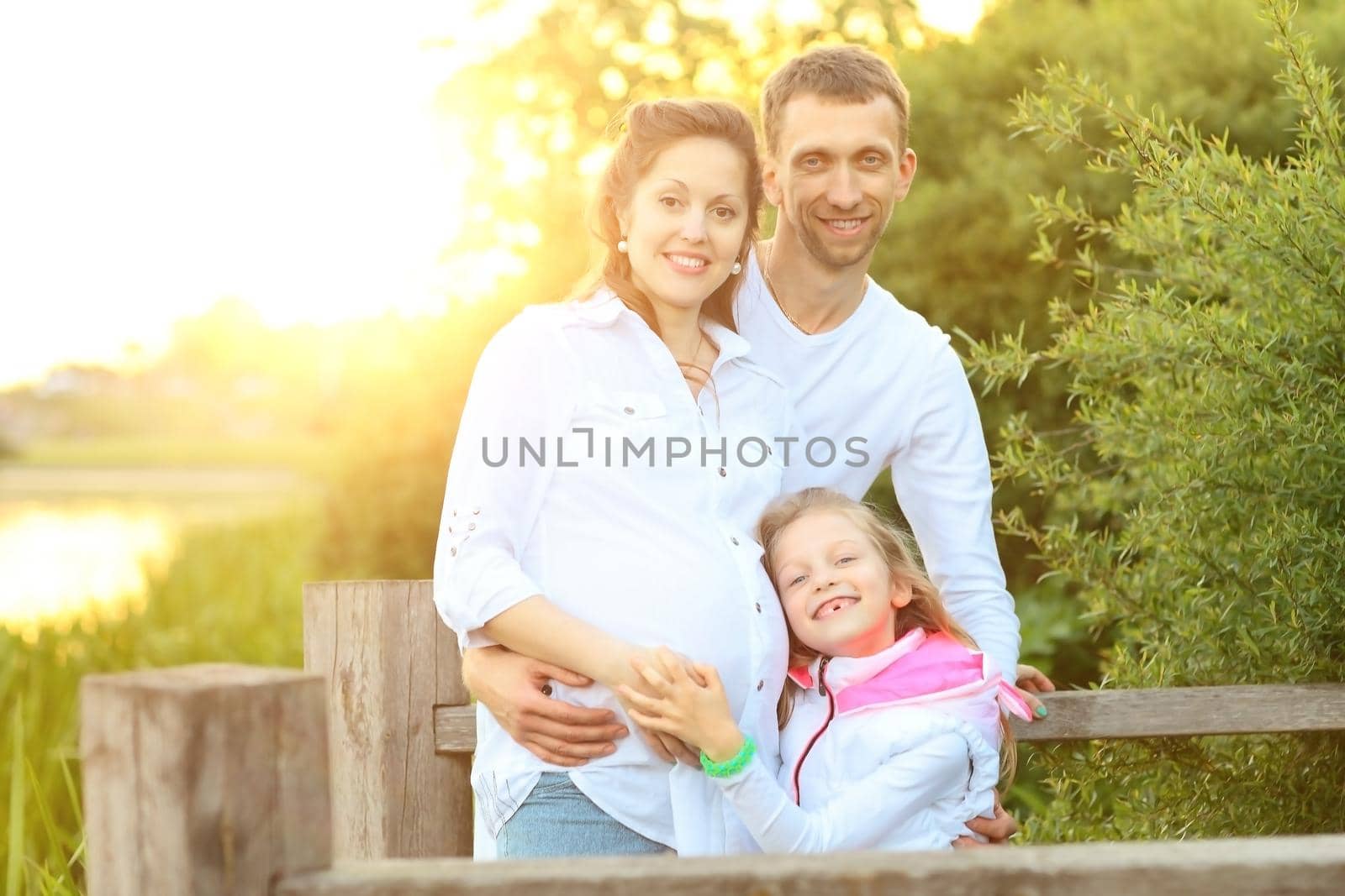 happy family father mother and daughter relax in the Park at sunset