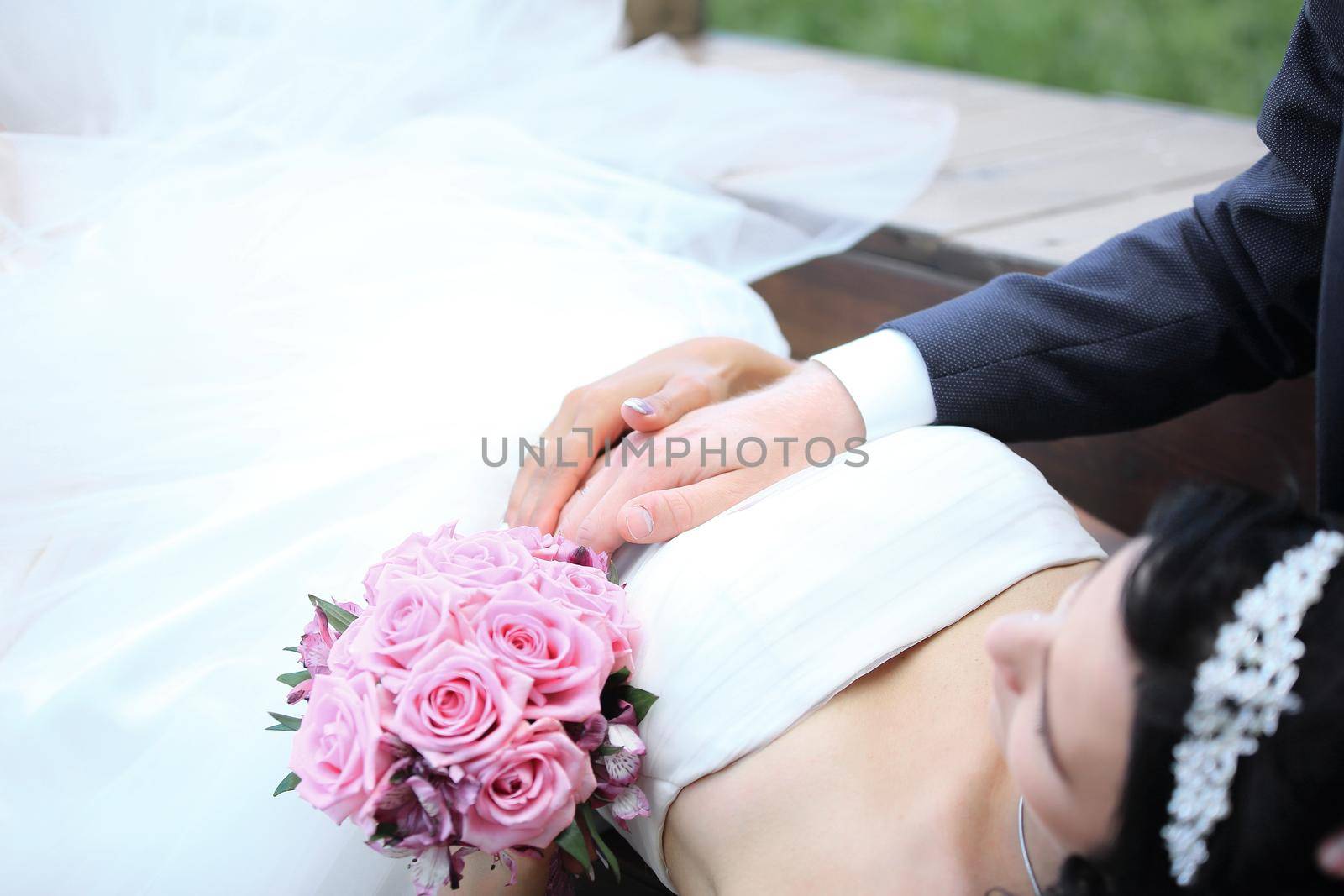 closeup of the bouquet and hands of the bride and groom with wedding rings