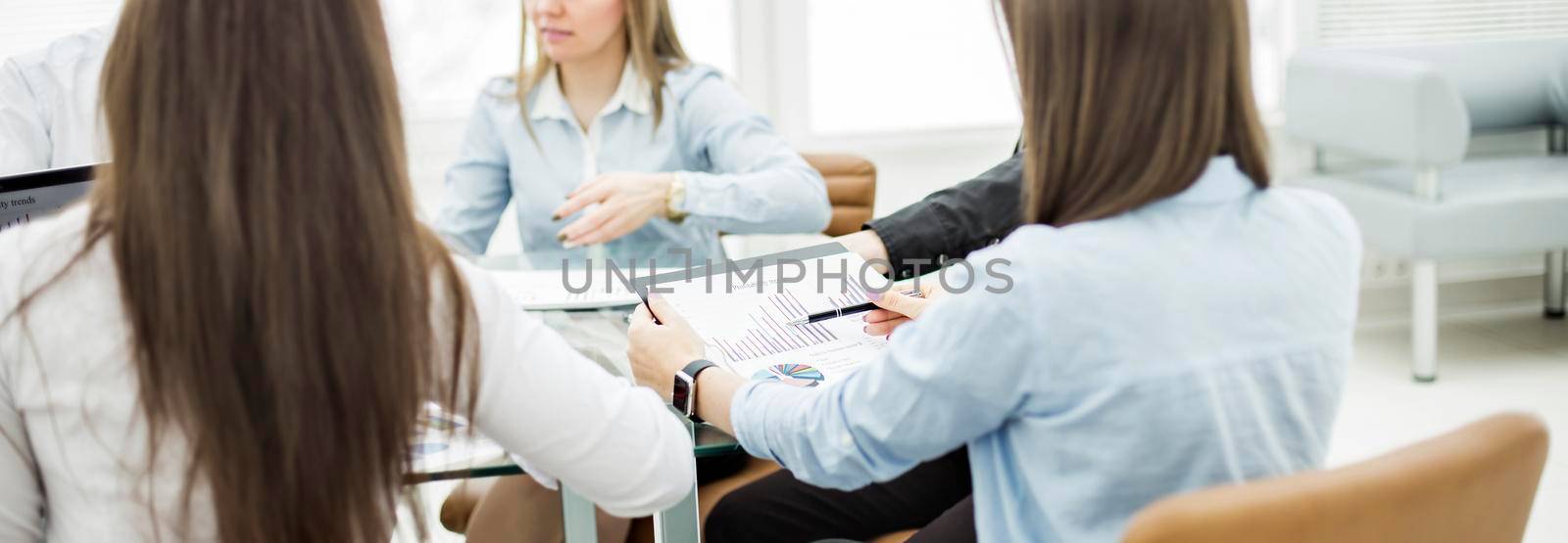 business team at a working conference sitting at a Desk and discussing important issues by SmartPhotoLab