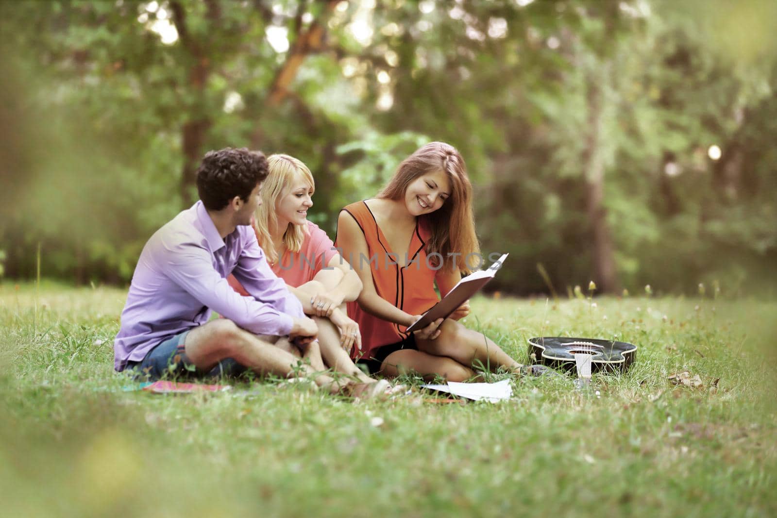 successful group of students with notebooks at the Park with a book in the guitar