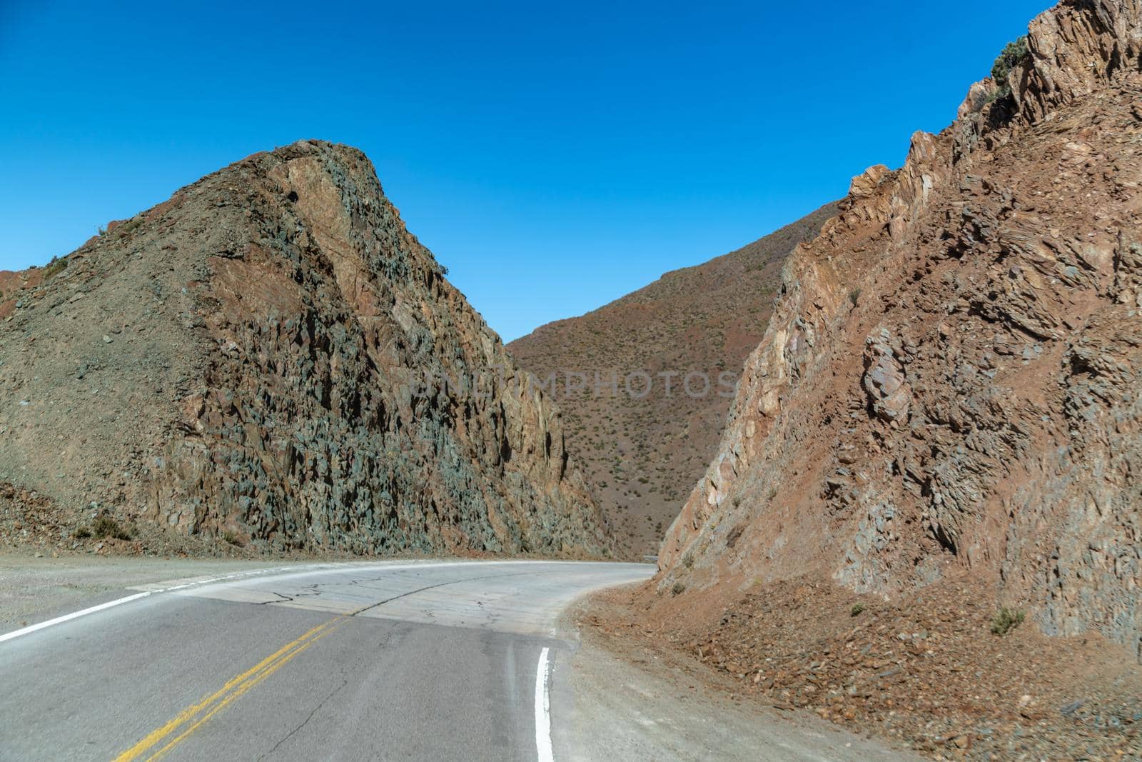 road in the mountains between the cliffs overlooking the snowy hills.