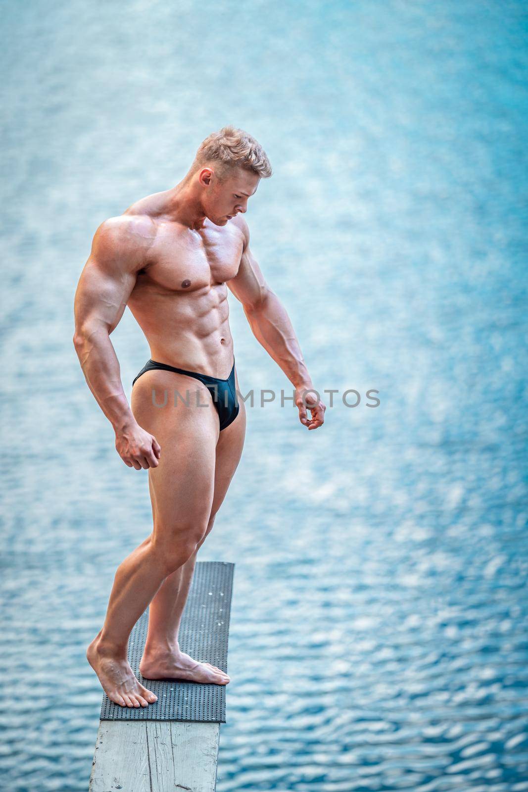 male bodybuilder by the water in nature.