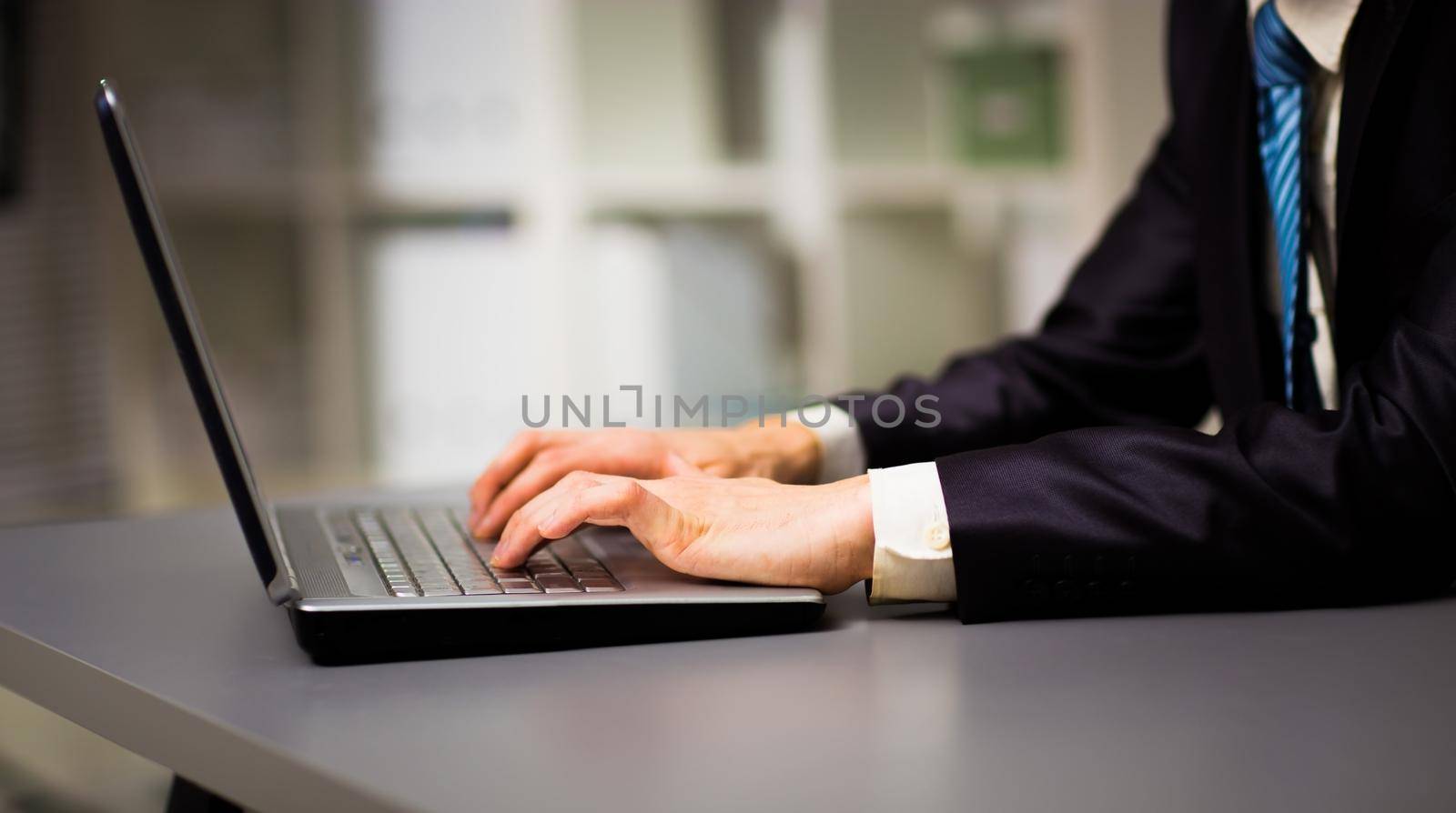 Person Typing on a modern laptop in the office by SmartPhotoLab