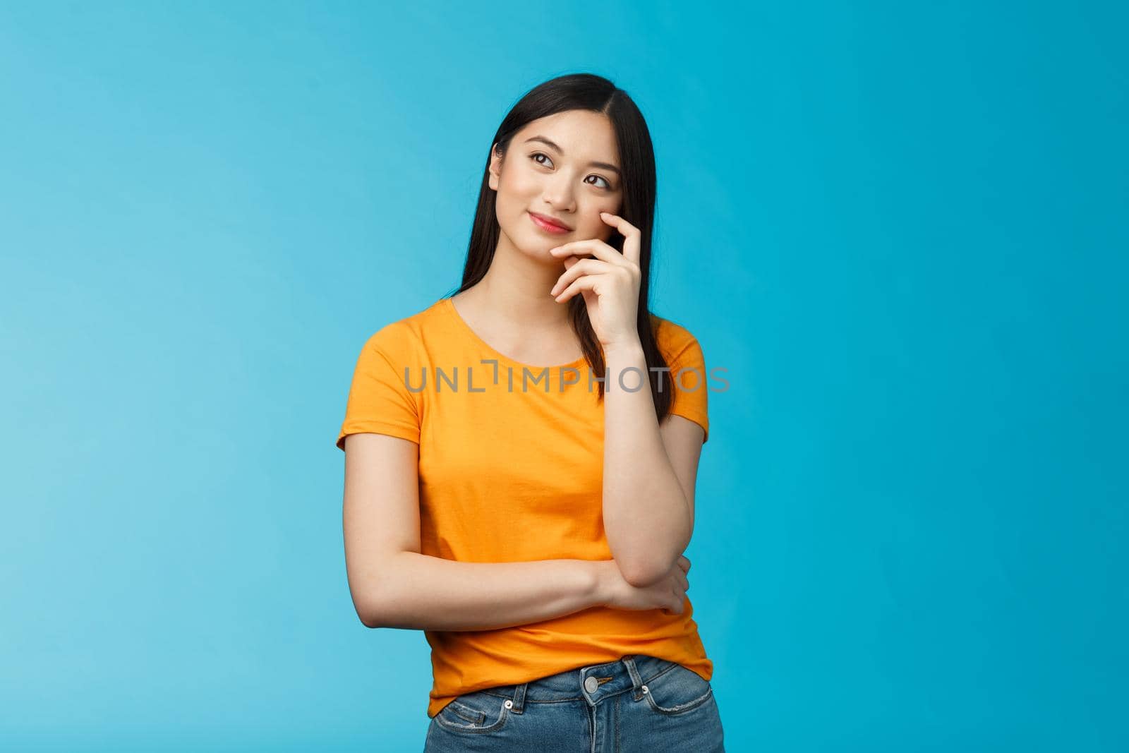 Joyful confident asian girl with dark haircut tilt head, dreaming, imaging interesting plan, smiling cunning, have idea, thinking and making choice, look up thoughtful, stand blue background by Benzoix