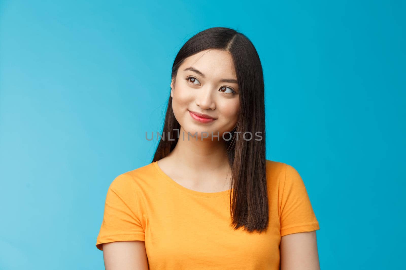 Close-up dreamy hopeful charming young asian woman wear yellow t-shirt turn sideways smiling delighted, contemplate beautiful summer scenery outside window sit office carefree, blue background.