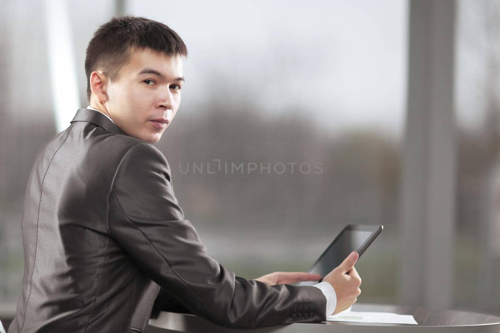 businessman with digital tablet sitting in a cafe near a large window.