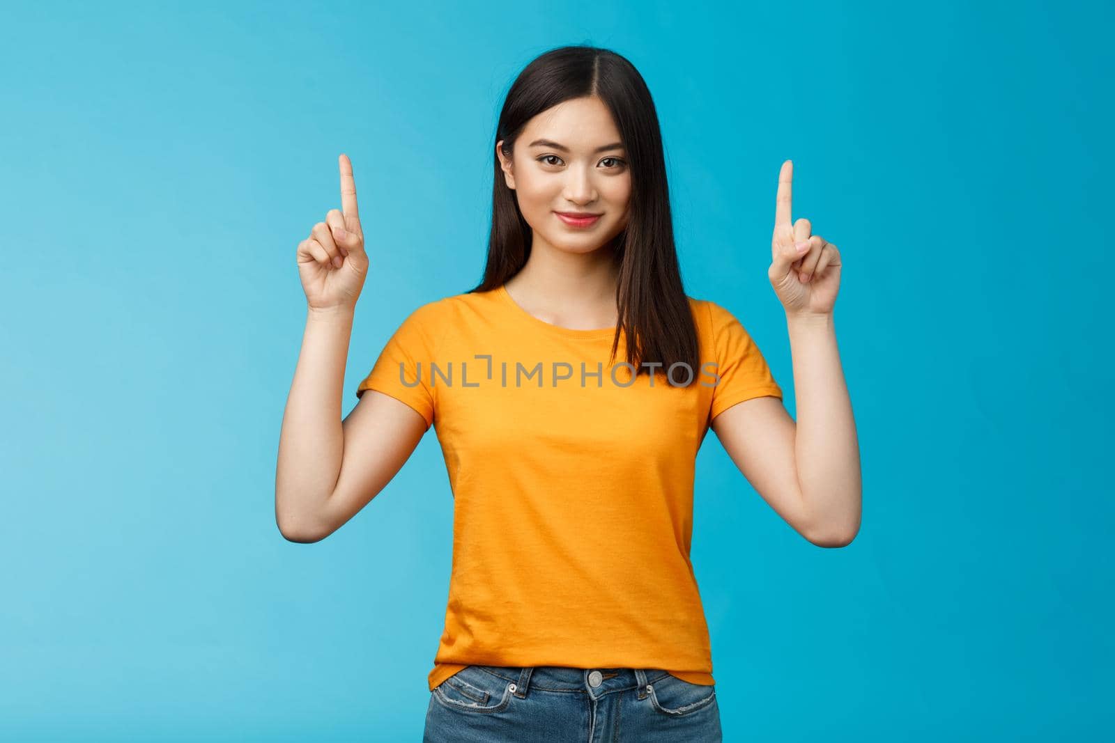 Heads up see awesome promo. Assertive good-looking confident asian woman showing friend advertisement, raise index fingers pointing top, smiling camera self-assured, stand blue background determined by Benzoix
