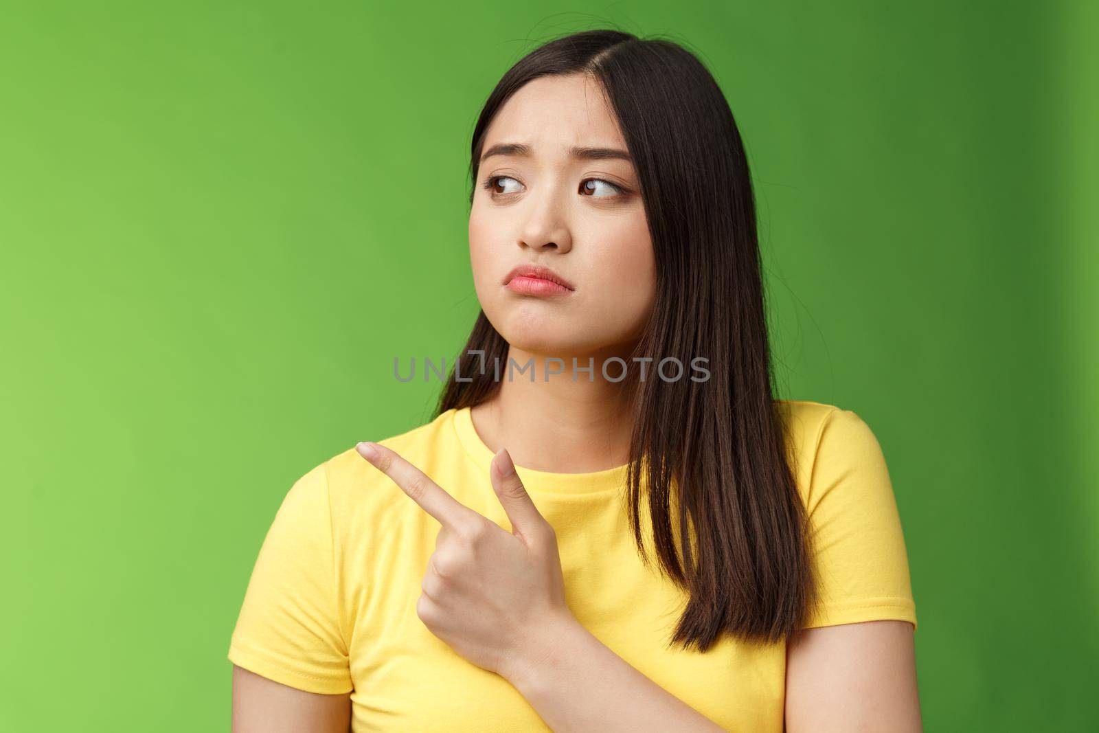 Gloomy upset lonely asian girl jealous sister pointing turn head left, sulking sighing sorrow distress, stand green background unhappy, feel unlucky and disappointed, regret not going concert by Benzoix