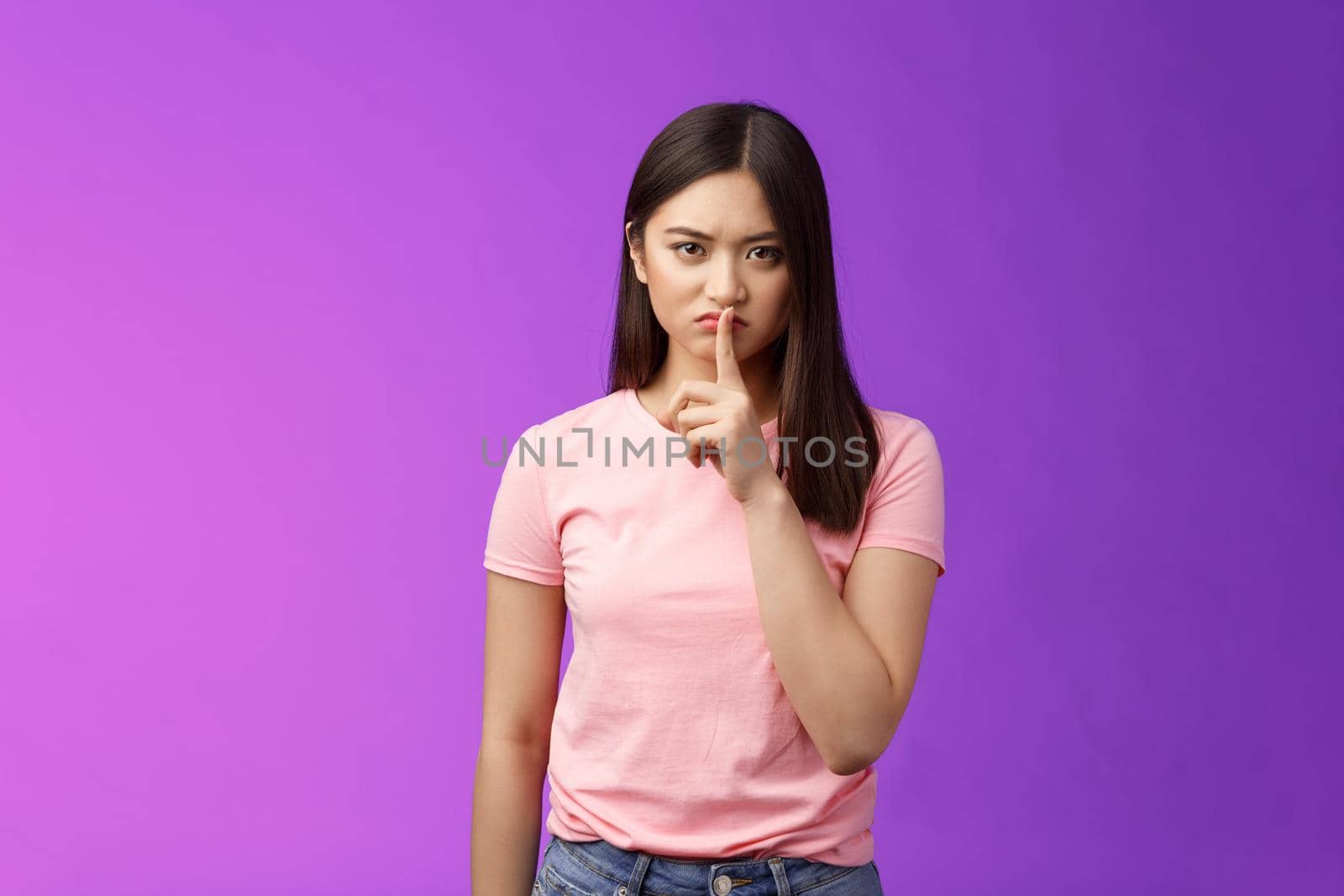 Shut up, seriously. Angry unsatisfied asian woman brunette frowning make hush sign, hold index finger on lips grimacing annoyed, prohibit speak, shushing stay silent, stand purple background by Benzoix