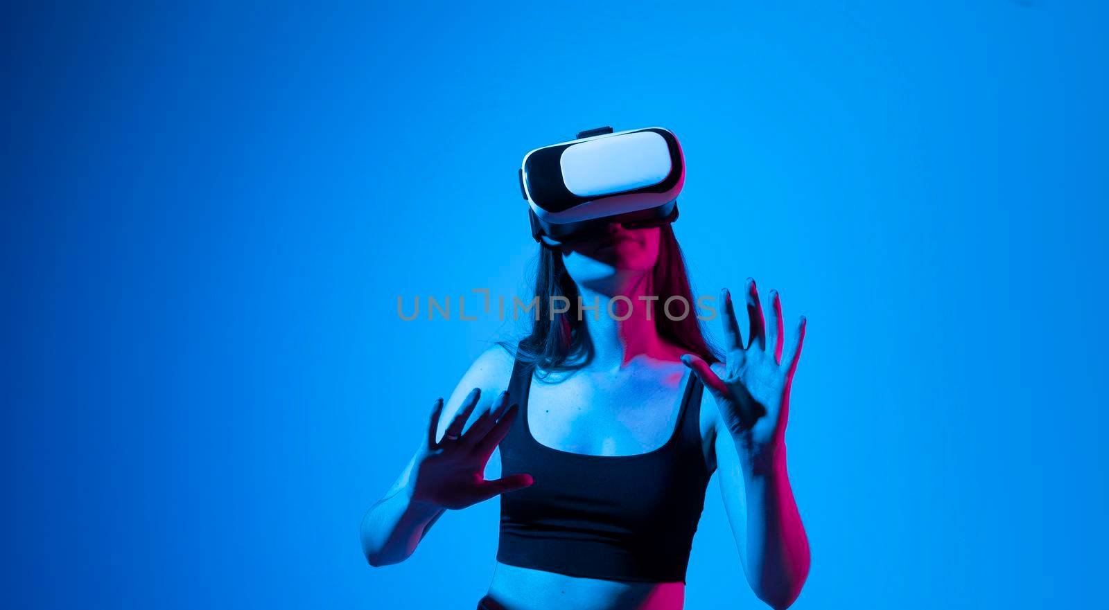 Brunette woman with VR headset touching something what she see in virtual world. Futuristic technology. Woman with glasses of virtual reality. Future technology concept. by vovsht