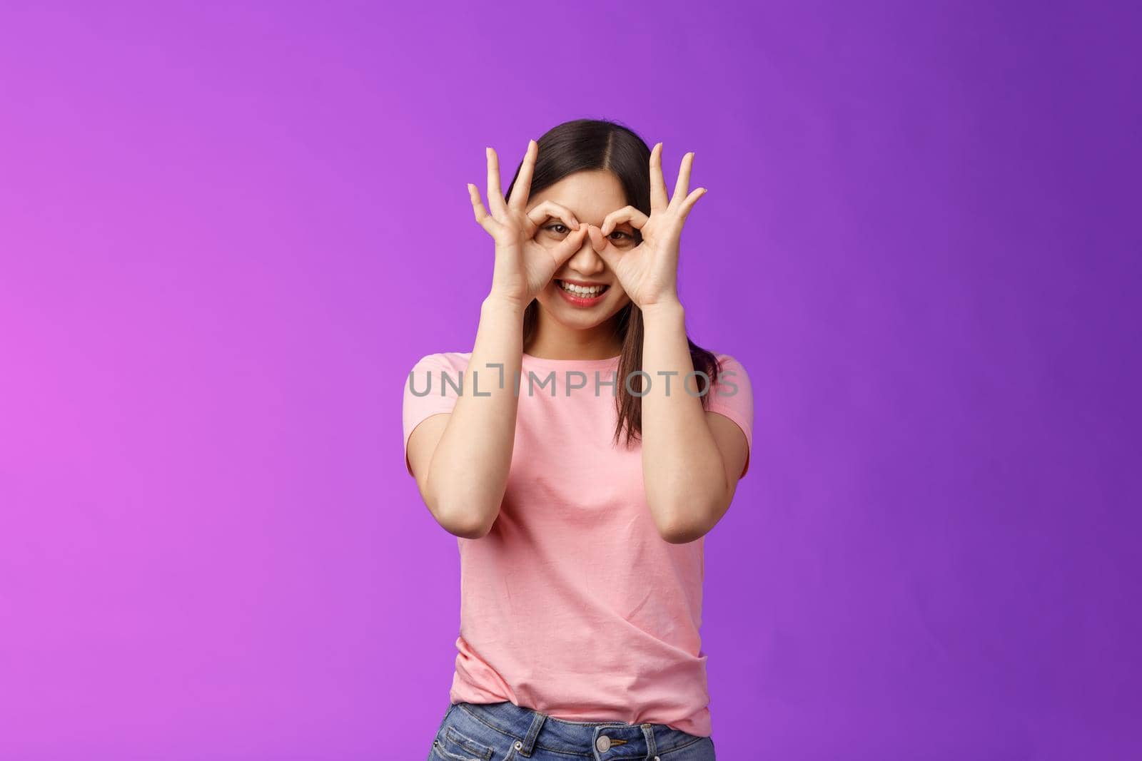 Cheerful friendly carefree asian woman having fun fool around, show okay ok signs on eyes make glasses from fingers, smiling delighted, mimicking funny emotions, stand purple background happy by Benzoix