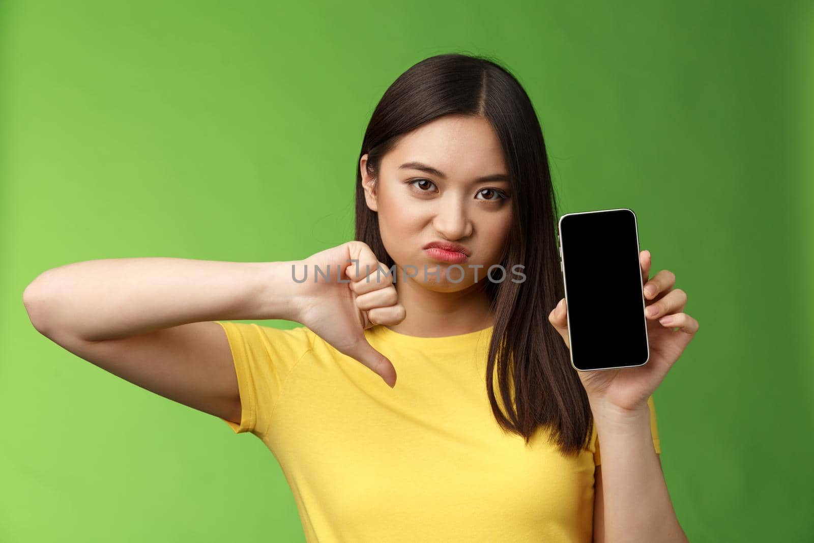 Close-up disappointed upset asian girl judging bad awful app, show smartphone screen, thumb-down grimacing displeased, give negative feedback, cannot stand ex-boyfriend new girlfriend.