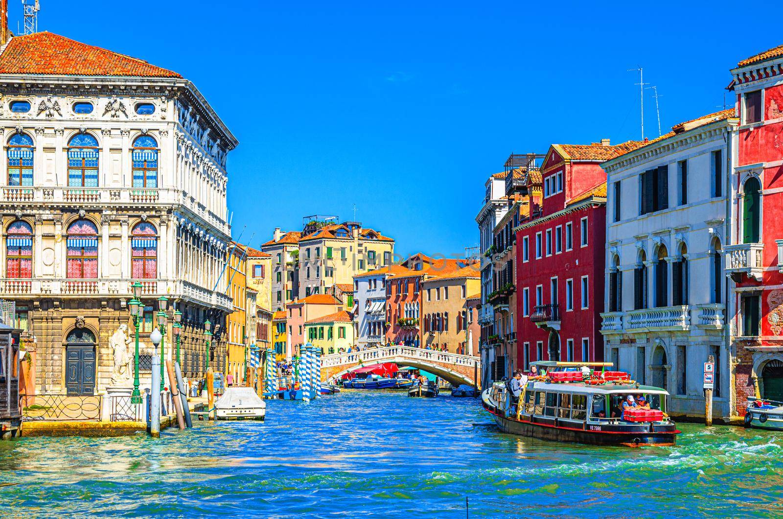 Venice, Italy, September 13, 2019: Grand Canal waterway across Cannaregio Canal with Palazzo Labia palace, Ponte delle Guglie bridge and vaporetto sailing in water, blue sky background in summer day