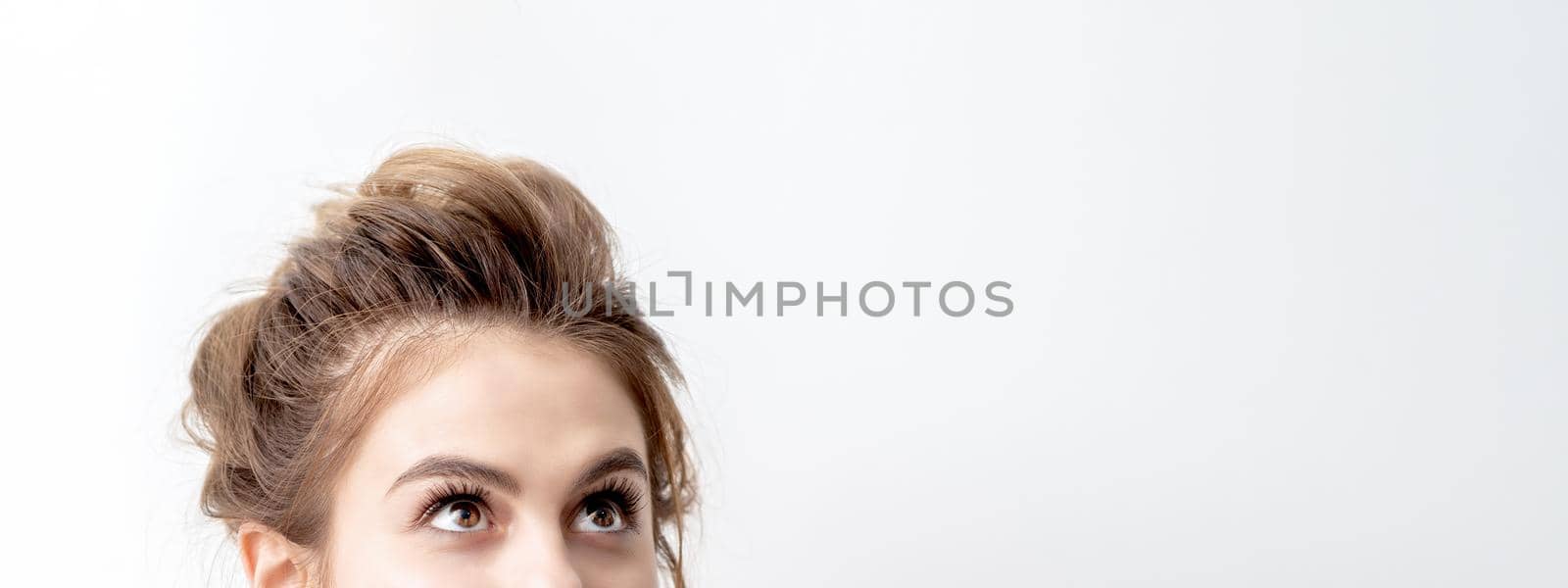 Half face of beautiful young caucasian woman looking up on white background. Girl looking upwards with copy space