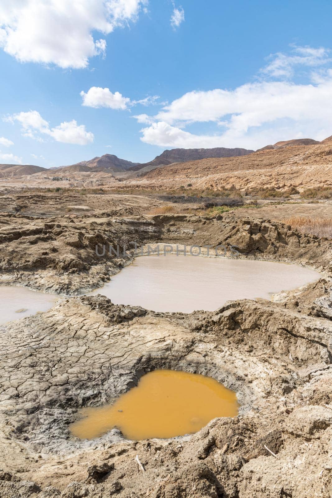 Sinkhole filled with water in different colors, near Dead Sea coastline. Hole formed when underground salt is dissolved by freshwater intrusion, due to continuing sea-level drop. . High quality photo