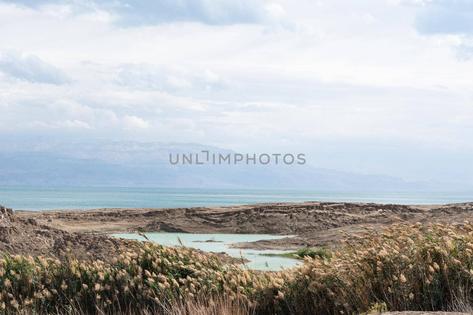 Sinkhole filled with turquoise water, near Dead Sea coastline. Hole formed when underground salt is dissolved by freshwater intrusion, due to continuing sea-level drop. . High quality photo