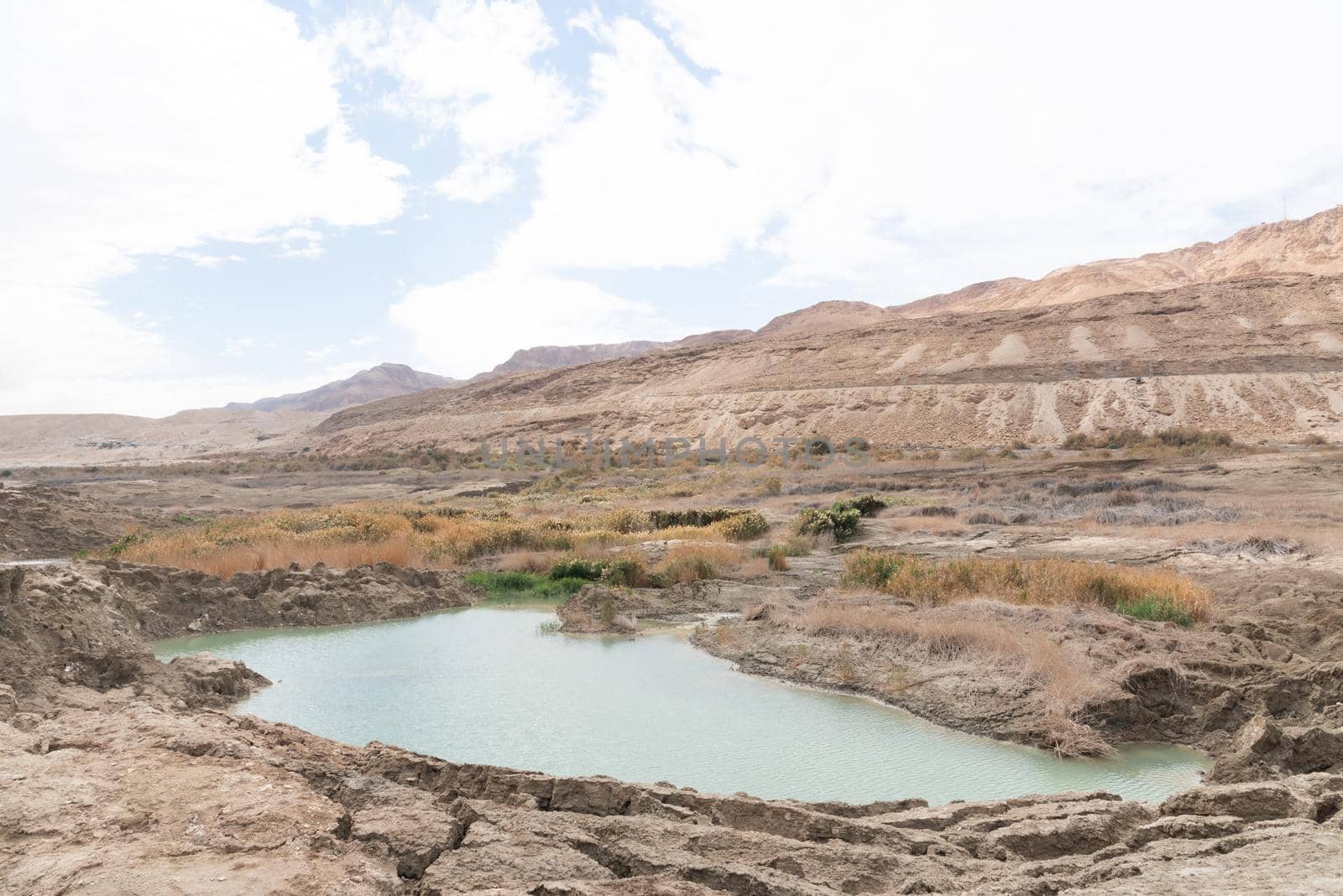 Sinkhole filled with turquoise water, near Dead Sea coastline. Hole formed when underground salt is dissolved by freshwater intrusion, due to continuing sea-level drop. . High quality photo