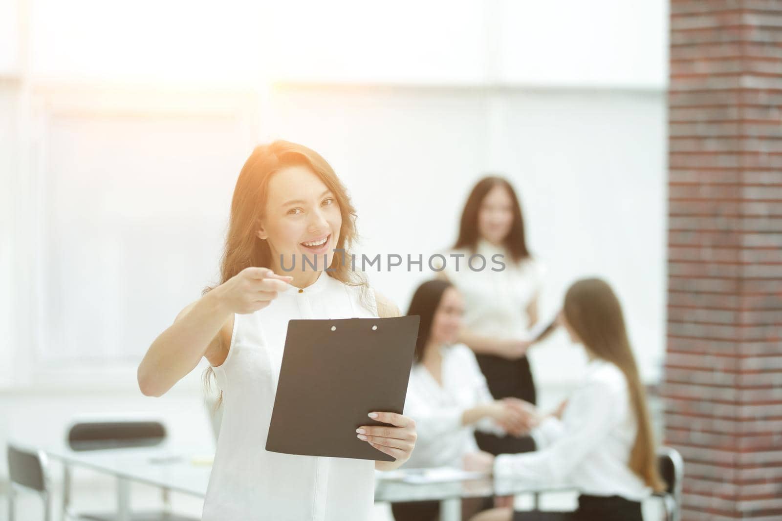 confident young business woman with clipboard on the background of business team by SmartPhotoLab