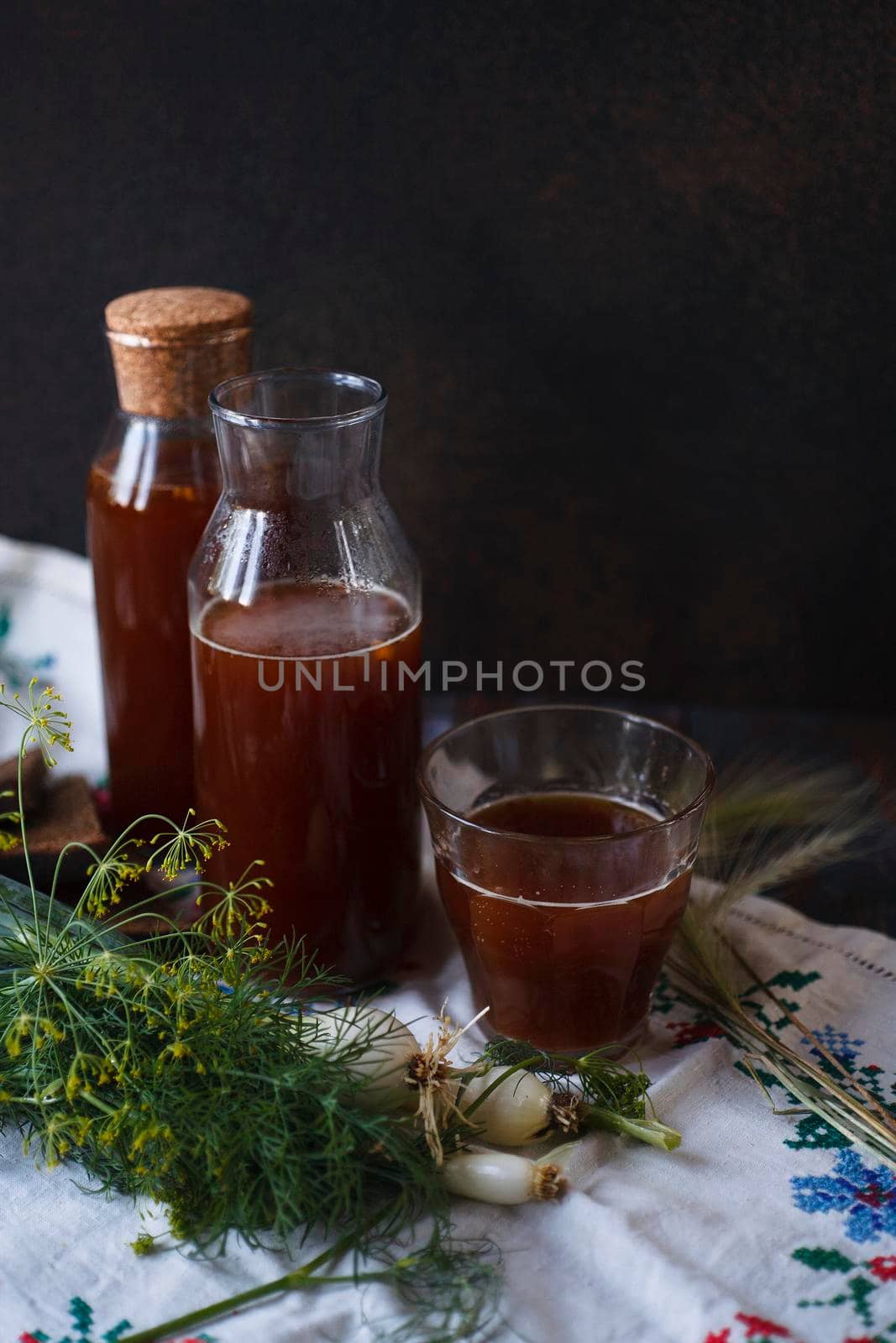 Bottles and a glass of kvass and slices of rye bread with fresh green onion and dill on white towel, traditional Russian drink, traditional folk meal concept, flat lay. selective focus