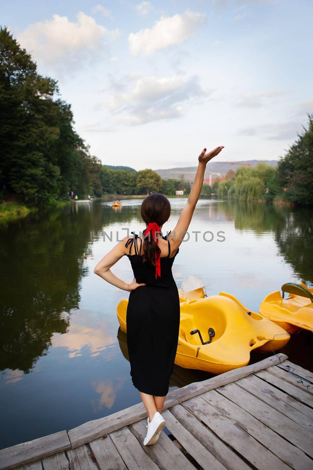 Portrait of a young beautiful European woman in a black dress standing on a city street in the city near the lake. European girl, beauty, fashion. by sfinks