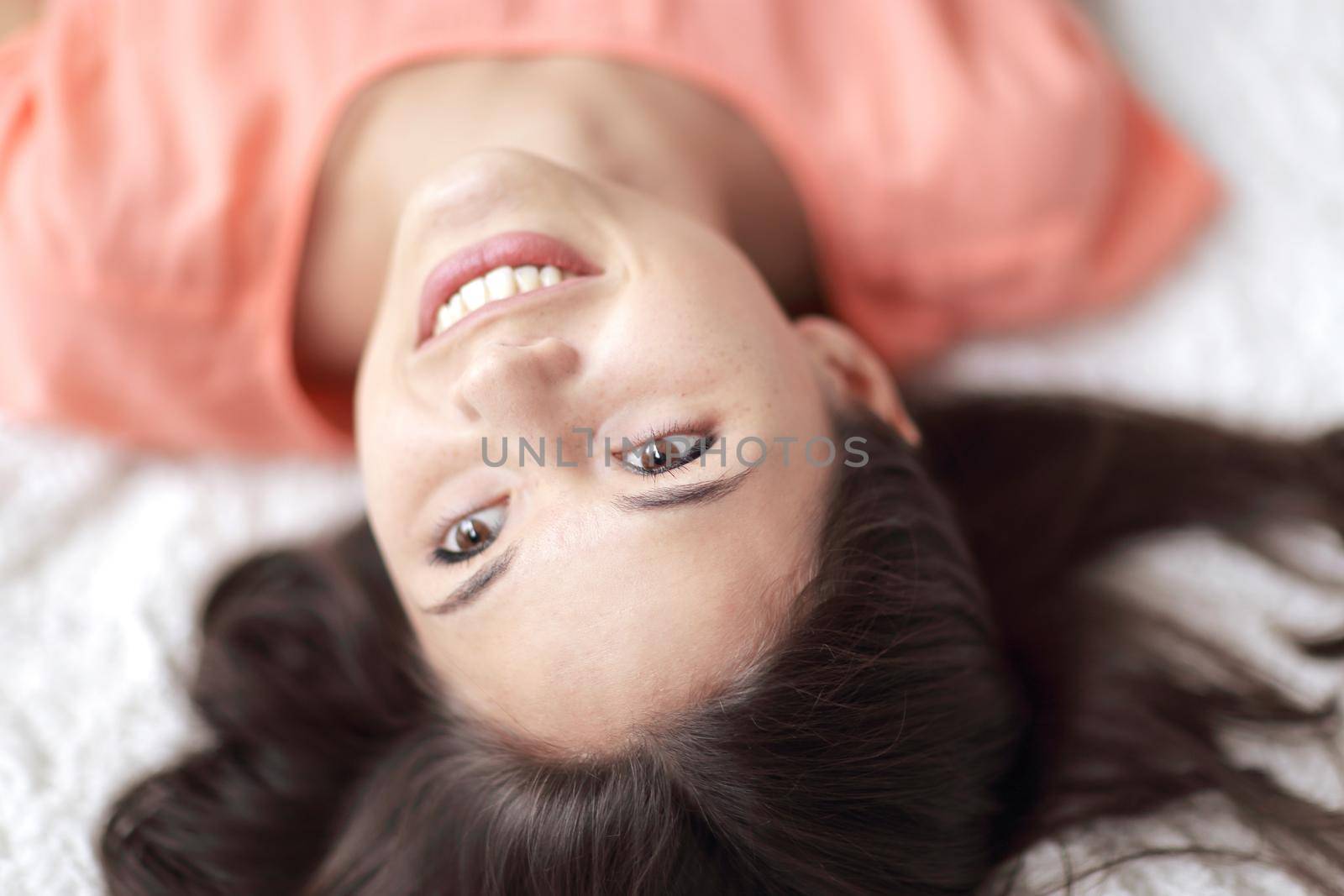 close up.portrait of young woman lying on white carpet in living room.
