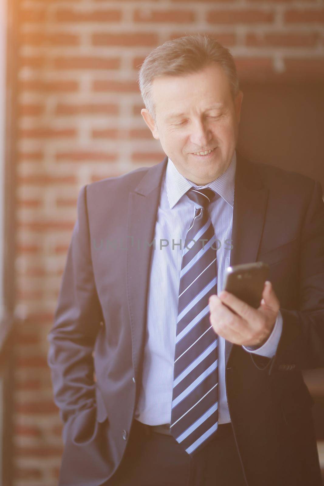 senior businessman reading text message on smartphone. by SmartPhotoLab
