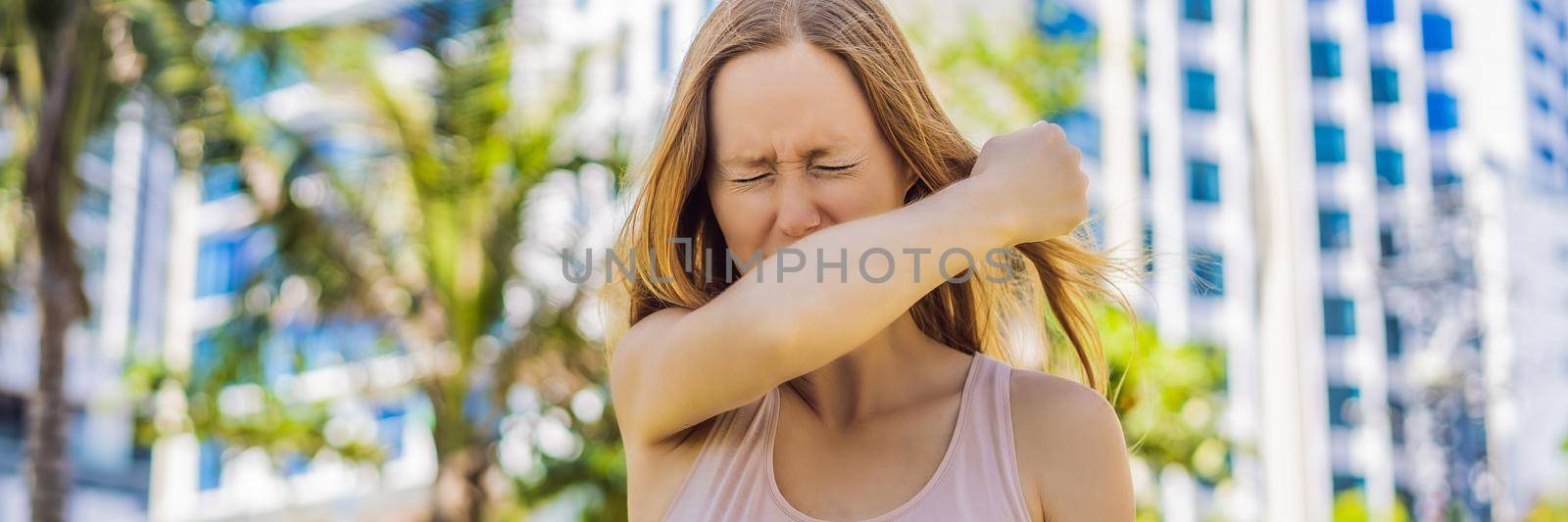 How to sneeze correctly. Woman sneezes on the elbow. Concept of the spread of the virus. BANNER, LONG FORMAT