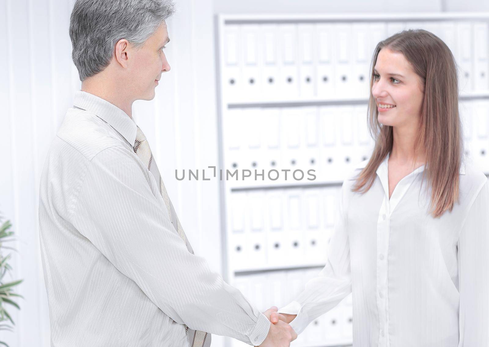 handshake of a businessman and a young employee of the company on the background of the office