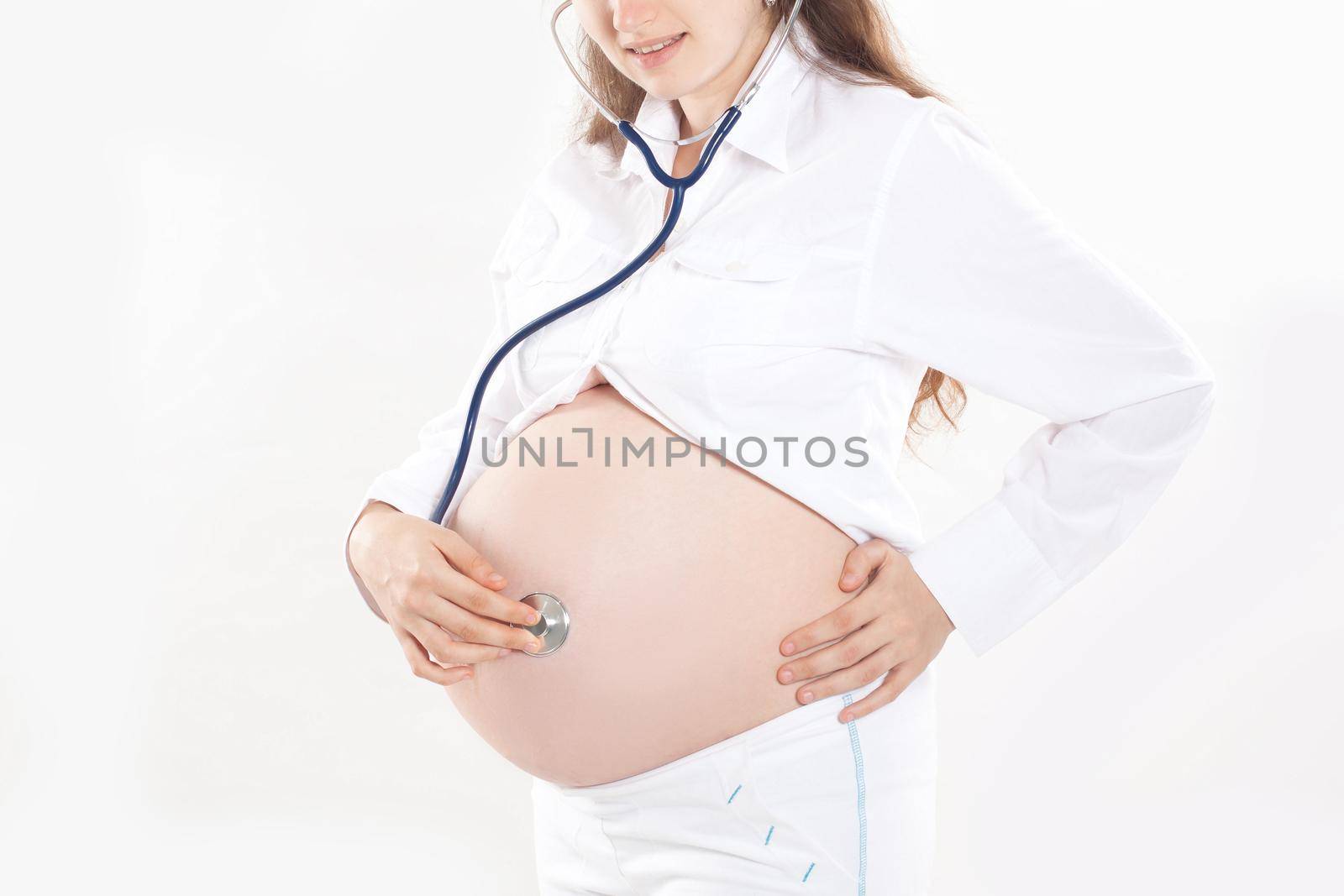 Pregnant woman listening through a stethoscope that makes her a child.isolated on white