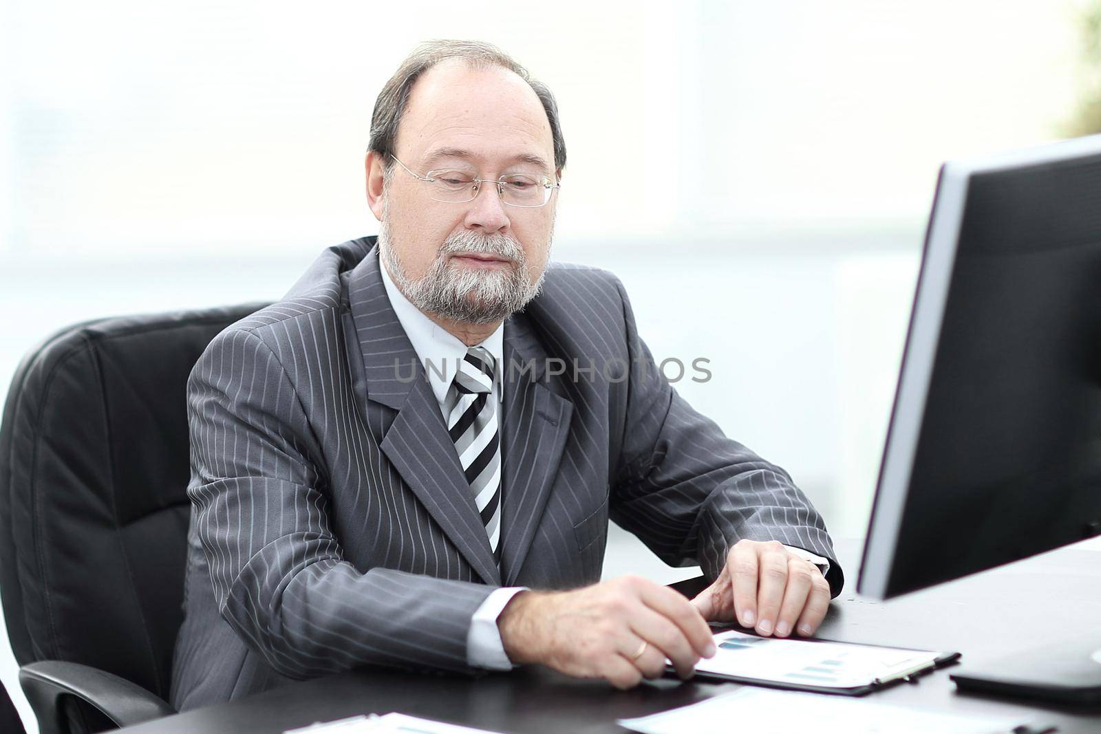 successful senior businessman sitting at his Desk by SmartPhotoLab