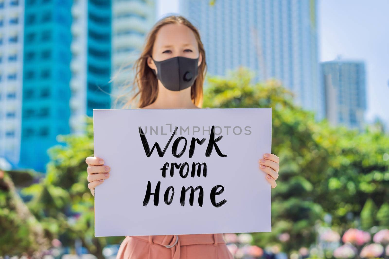 woman in medical mask prevents coronavirus disease holds a poster Work from home. Hand written text - lettering isolated on white. Coronovirus COVID 19 concept by galitskaya